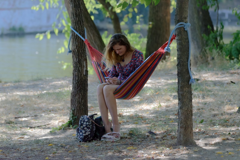 Woman sitting on hammock near a lake
